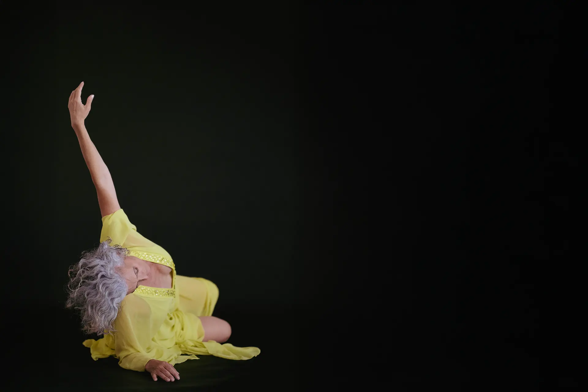 Emmanuelle Em in a yellow dress on a dark stage